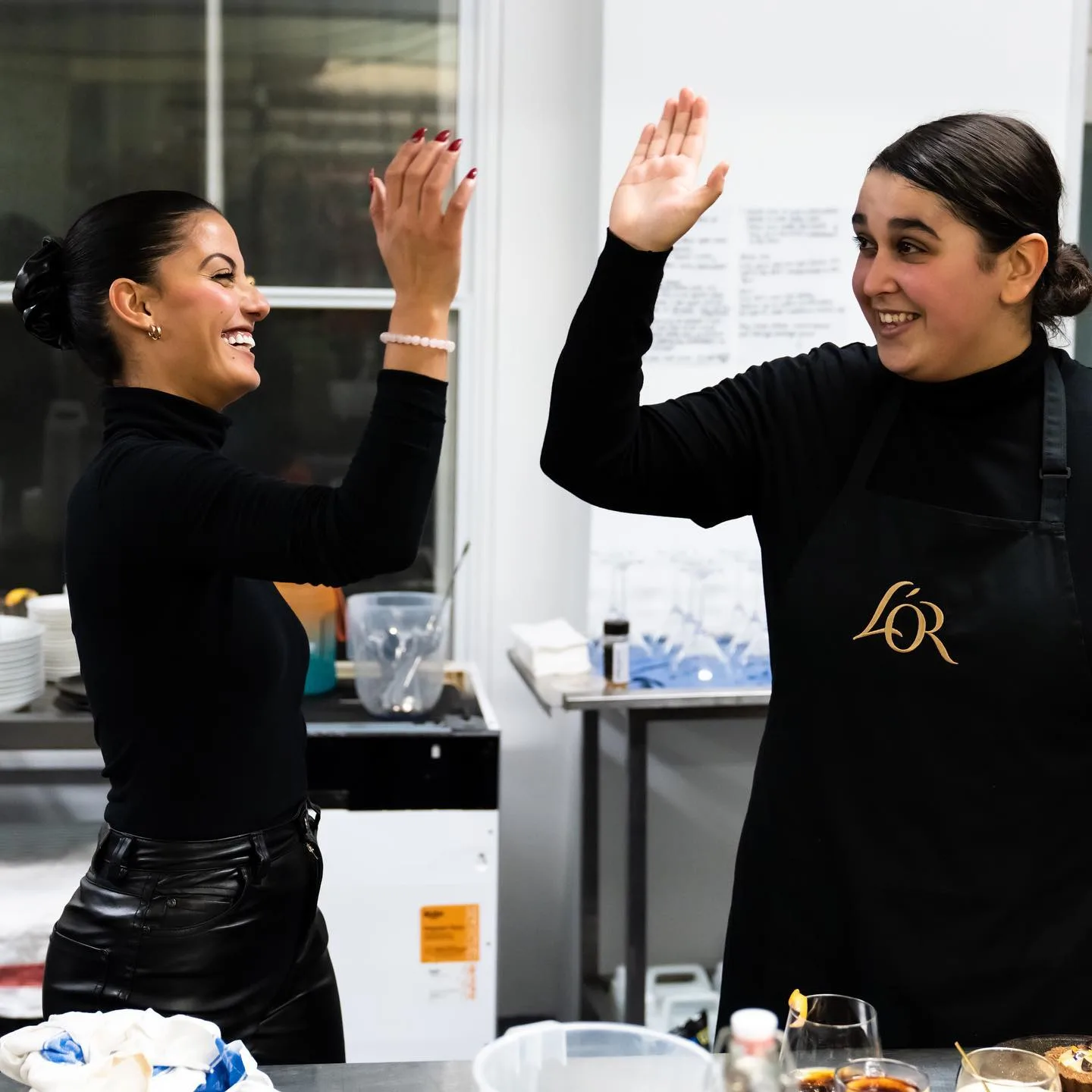 Two coffee shop team members celebrating with a high five in the kitchen